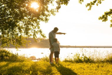 Baba deniz kenarında oğluyla oynuyor. Gün batımının ya da güneşin sıcacık renkleri.
