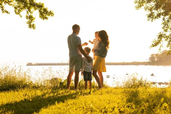 幸福的家庭在海边散步 乡间田地和树木 日落或日出的温暖颜色 慈爱的父母和美丽的孩子 爱和父母的概念 — 图库照片