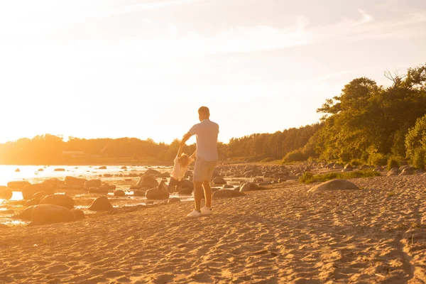 父亲和他的儿子在海边玩耍 日落或日出的暖色 — 图库照片
