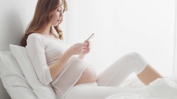 Mujer Embarazada Feliz Usando Dispositivo Teléfono Inteligente Sentado Cama Concepto — Vídeo de stock