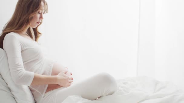Boldog Terhes Fogdossa Gyönyörű Hasát Ágyban Ülve Terhesség Anyaság Elvárás — Stock videók