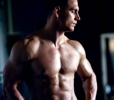 Siyah arka plan üzerinde güçlü, formda ve sporcu bir vücut geliştirici. Spor ve spor konsepti.