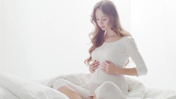 Szczęśliwa Ciężarna Kobieta Dotykająca Swojego Pięknego Brzucha Siedzącego Łóżku Ciąża — Wideo stockowe