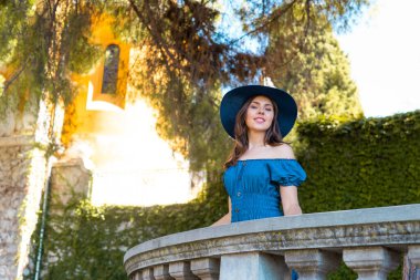 Parkta gezen genç ve güzel esmer elbiseli ve şapkalı kız. Güzel, France. Yaz tatili, seyahat ve turizm konsepti.