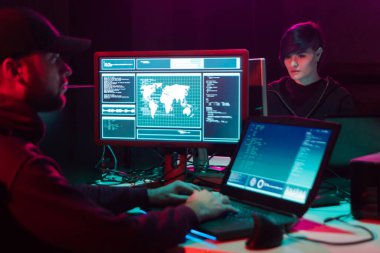 Aranan hackerlar virüs fidye yazılımını bodrumdaki bilgisayar ve dizüstü bilgisayarlarla kodluyorlar. Siber saldırı, sistem kırma ve kötü amaçlı yazılım kavramı.