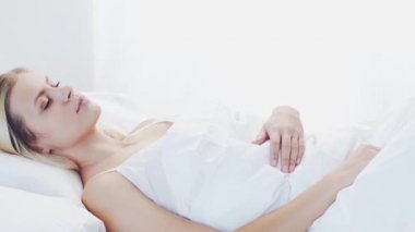 Yatakta yatan genç bir kadın. Güzel sarışın, uyuyan kız. Yatak odasında sabah, pencereden gün ışığı. Sağlık ve dinlenme kavramı.