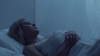 Genç bir kadın geceleri yatakta uzanıyor ve uykusuzluk hastalığına yakalanıyor. Güzel sarışın, uyuyan kız. Yatak odasında alacakaranlık, pencereden ay ışığı. Uykusuzluk, sağlık ve dinlenme kavramı.
