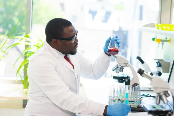 アフリカ系アメリカ人の科学者が研究室で働いている 微生物学の研究を行う医師 研究室のツール 顕微鏡 試験管 生物学 細菌学 ウイルス学 Dnaと健康 — ストック写真