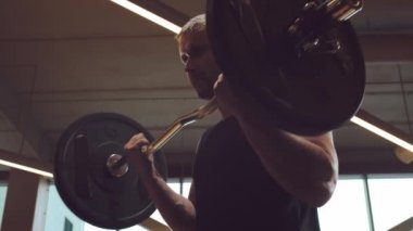 Spor salonunda halter kullanarak çalışan yakışıklı erkek sporcu. Güçlü ve sağlıklı vücut geliştirici abdominal eğitim egzersizleri. Spor, spor, spor ve yaşam tarzı konsepti.