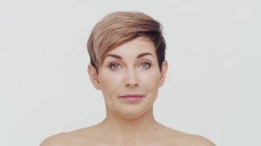 Beyaz arka planda orta yaşlı olgun bir kadının yakın çekimi. Olgun bir kadının portresi. Estetik cerrahi, güzellik enjeksiyonları, kozmetoloji konsepti.