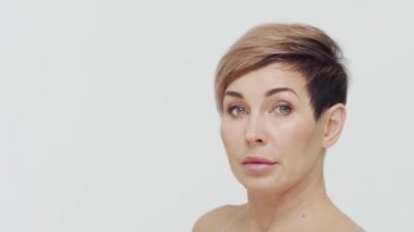 Beyaz arka planda orta yaşlı olgun bir kadının yakın çekimi. Olgun bir kadının portresi. Estetik cerrahi, güzellik enjeksiyonları, kozmetoloji konsepti.