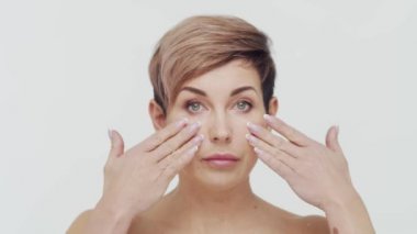 Beyaz arka planda orta yaşlı olgun bir kadının yakın çekimi. Olgun bir kadının portresi. Estetik cerrahi, güzellik enjeksiyonları, kozmetoloji konsepti.