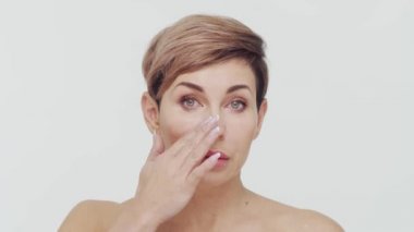 Beyaz arka planda orta yaşlı olgun bir kadının yakın çekimi. Olgun bir kadının portresi. Estetik cerrahi, güzellik enjeksiyonları, kozmetoloji konsepti.