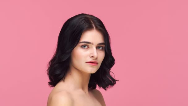 ピンクの背景に若いと美しいブルネットの女性のスタジオの肖像画 スキンケア 化粧品の概念 — ストック動画