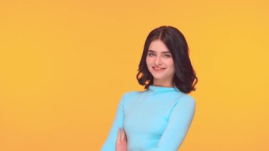 Sarı arka planda genç ve etkileyici esmer kızın stüdyo portresi..