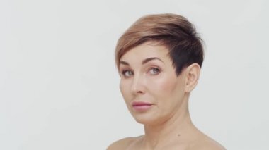 Beyaz arka planda orta yaşlı olgun bir kadının yakın çekimi. Olgun bir kadının portresi. Estetik cerrahi, güzellik enjeksiyonları, kozmetoloji konsepti.