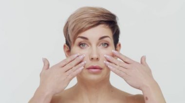 Beyaz arka planda orta yaşlı olgun bir kadının yakın çekimi. Olgun bir kadının portresi. Estetik cerrahi, güzellik enjeksiyonları, kozmetoloji konsepti.