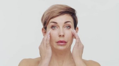 Beyaz arka planda orta yaşlı olgun bir kadının yakın çekimi. Olgun bir kadının portresi. Estetik cerrahi, güzellik enjeksiyonları, kozmetoloji konsepti.