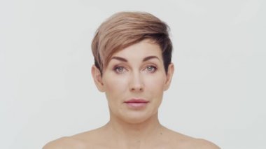 Beyaz arka planda orta yaşlı olgun bir kadının yakın çekimi. Olgun bir kadının portresi. Estetik cerrahi, güzellik enjeksiyonları, kozmetoloji konsepti.