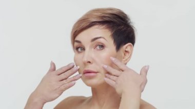 Beyaz arka planda orta yaşlı olgun bir kadının yakın çekimi. Olgun bir kadının portresi. Estetik cerrahi, güzellik enjeksiyonları, kozmetoloji konsepti.