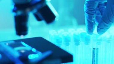 Mikroskop ve üzerinde kan ve virüs olan laboratuvar tüpü. Bilimsel laboratuvar yakın plan. Salgın hastalıklar, sağlık hizmetleri, aşı araştırmaları ve Coronavirus covid-19 test konsepti.