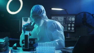Laboratuvar ekipmanları, mikroskoplar ve test tüpleri kullanarak araştırma laboratuarında çalışan koruyucu giysi ve maskeler giyen bilim adamları. Coronavirus 2019-ncov tehlikesi, ilaç keşfi, bakteri bilimi ve virüs bilimi