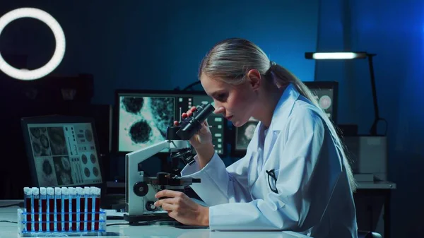 Scientist working in lab. Female doctor making medical research. Laboratory tools: microscope, test tubes, equipment. Coronavirus 2019-ncov, biotechnology, science, experiments and healthcare concept.