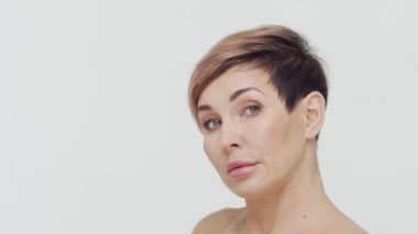 Beyaz arka planda orta yaşlı olgun bir kadının yakın çekimi. Olgun bir kadının portresi. Estetik cerrahi, güzellik enjeksiyonları, kozmetoloji konsepti.