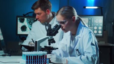 Laboratuvarda çalışan tıp bilimcileri. Doktor stajyerlere kan analizi yapmayı öğretiyor. Laboratuvar aletleri: mikroskop, test tüpleri, ekipmanlar. Koronavirüs, biyoteknoloji, bakteriyoloji, viroloji ve