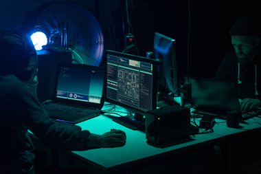 Aranan hackerlar virüs fidye yazılımını bodrumdaki bilgisayar ve dizüstü bilgisayarlarla kodluyorlar. Siber saldırı, sistem kırma ve kötü amaçlı yazılım kavramı.