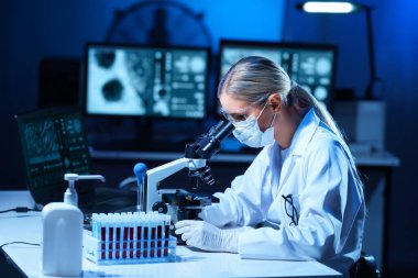 Laboratuvarda çalışan bir bilim adamı. Kadın doktor tıbbi araştırma yapıyor. Laboratuvar aletleri: mikroskop, test tüpleri, ekipmanlar. Coronavirus 2019-ncov, biyoteknoloji, bilim, deneyler ve sağlık konsepti.