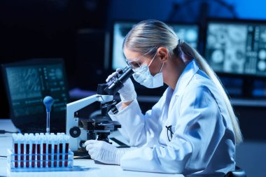 Modern laboratuarda çalışan kadın bilim adamı. Doktor mikrobiyoloji araştırması yapıyor. Laboratuvar aletleri: mikroskop, test tüpleri, ekipmanlar. Coronavirus covid-19, bakteriyoloji, viroloji, DNA ve sağlık hizmetleri.