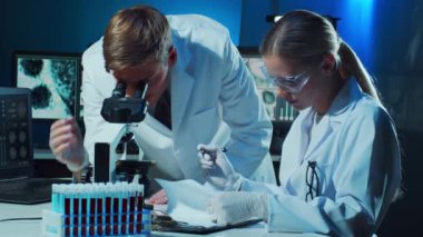 Laboratuvarda çalışan tıp bilimcileri. Doktor stajyerlere kan analizi yapmayı öğretiyor. Laboratuvar aletleri: mikroskop, test tüpleri, ekipmanlar. Koronavirüs, biyoteknoloji, bakteriyoloji, viroloji ve