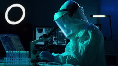 Laboratuvar ekipmanları, mikroskoplar ve test tüpleri kullanarak araştırma laboratuarında çalışan koruyucu giysi ve maskeler giyen bilim adamları. Coronavirus SARS-CoV-2 tehlikesi, ilaç keşfi, bakteri bilimi ve viroloji