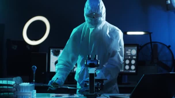 研究室の機器を使用して研究室で働く保護スーツやマスクの科学者 顕微鏡 試験管 コロナウイルスCovid 19危険性 医薬品の発見 細菌学およびウイルス学 — ストック動画