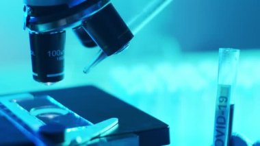 Mikroskop ve üzerinde kan ve virüs olan laboratuvar tüpü. Bilimsel laboratuvar yakın plan. Salgın hastalıklar, sağlık hizmetleri, aşı araştırmaları ve Coronavirus covid-19 test konsepti.