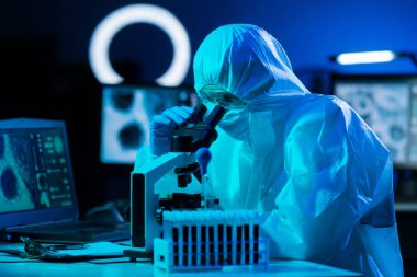 Laboratuvar ekipmanları, mikroskoplar, test tüpleri kullanarak araştırma laboratuarında çalışan koruyucu giysiler ve maskeler giyen bilim adamları. Coronavirus covid-19 tehlike, ilaç keşfi, bakteri bilimi ve virüs bilimi