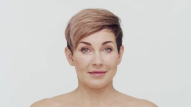 Beyaz arka planda orta yaşlı olgun bir kadının yakın çekimi. Olgun bir kadının portresi. Estetik cerrahi, güzellik enjeksiyonları, kozmetoloji konsepti.