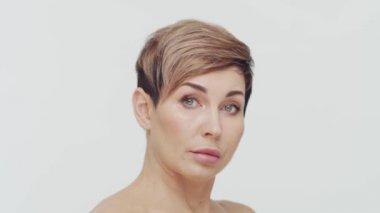 Beyaz arka planda orta yaşlı olgun bir kadının yakın çekimi. Olgun bir kadının portresi. Estetik cerrahi, güzellik enjeksiyonları, kozmetoloji konsepti.