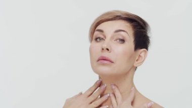 Beyaz arka planda orta yaşlı olgun bir kadının yakın çekimi. Olgun bir kadının portresi. Estetik cerrahi, güzellik enjeksiyonları, kozmetoloji konsepti.