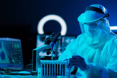 Laboratuvar ekipmanları, mikroskoplar, test tüpleri kullanarak araştırma laboratuarında çalışan koruyucu giysiler ve maskeler giyen bilim adamları. Coronavirus covid-19 tehlike, ilaç keşfi, bakteriyoloji ve virüs bilimi konsepti.