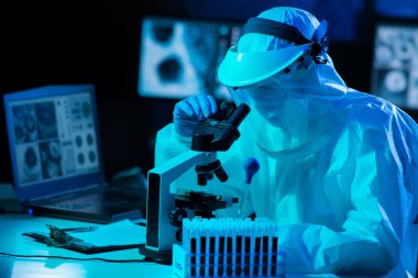 Laboratuvar ekipmanları, mikroskoplar, test tüpleri kullanarak araştırma laboratuarında çalışan koruyucu giysiler ve maskeler giyen bilim adamları. Coronavirus covid-19 tehlike, ilaç keşfi, bakteriyoloji ve virüs bilimi konsepti.