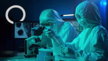 Laboratuvarda çalışan koruyucu giysi ve maskeli bilim adamları laboratuvar ekipmanları kullanıyorlardı: mikroskop, test tüpleri. İlaç, koronavirüs 2019-ncov enfeksiyonu ve aşı keşfi konsepti.