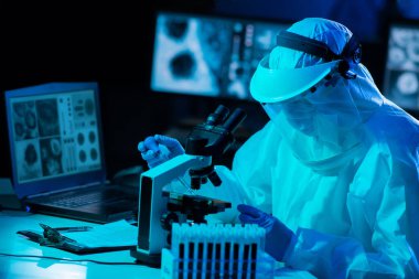 Laboratuvar ekipmanları, mikroskoplar ve test tüpleri kullanarak araştırma laboratuarında çalışan koruyucu giysi ve maskeler giyen bilim adamları. Coronavirus 2019-ncov tehlikesi, ilaç keşfi, bakteri bilimi ve virüs bilimi