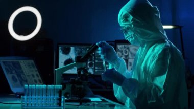 Laboratuvar ekipmanları, mikroskoplar ve test tüpleri kullanarak araştırma laboratuarında çalışan koruyucu giysi ve maskeler giyen bilim adamları. Coronavirus 2019-ncov tehlikesi, ilaç keşfi, bakteri bilimi ve virüs bilimi