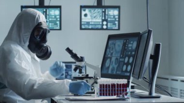 Laboratuvar ekipmanları, mikroskoplar, test tüpleri kullanarak araştırma laboratuarında çalışan koruyucu giysiler ve maskeler giyen bilim adamları. Coronavirus covid-19 tehlike, ilaç keşfi, bakteri bilimi ve virüs bilimi