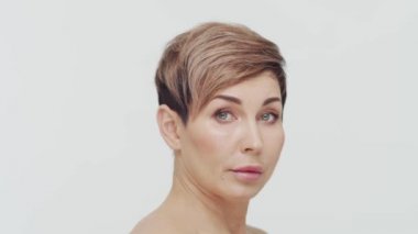 Beyaz arka planda orta yaşlı olgun bir kadının yakın çekimi. Olgun bir kadının portresi. Estetik cerrahi, güzellik enjeksiyonları, kozmetoloji konsepti.