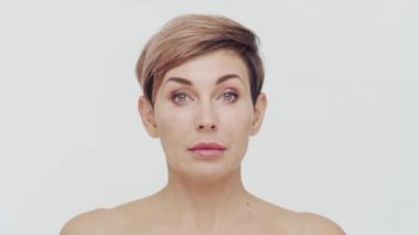 Beyaz arka planda orta yaşlı olgun bir kadının yakın çekimi. Olgun bir kadının portresi. Estetik cerrahi, güzellik enjeksiyonları, kozmetoloji konsepti.