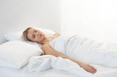 Yatakta yatan genç bir kadın. Güzel sarışın, uyuyan kız. Yatak odasında sabah, pencereden gün ışığı. Sağlık ve dinlenme kavramı.