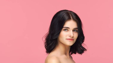 Pembe arka planda genç ve güzel esmer kadının stüdyo portresi. Cilt bakımı, sağlık, makyaj ve kozmetik konsepti.